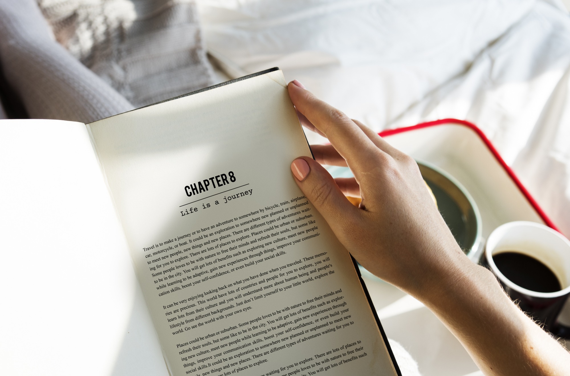 A person reading a book while sitting on a bed